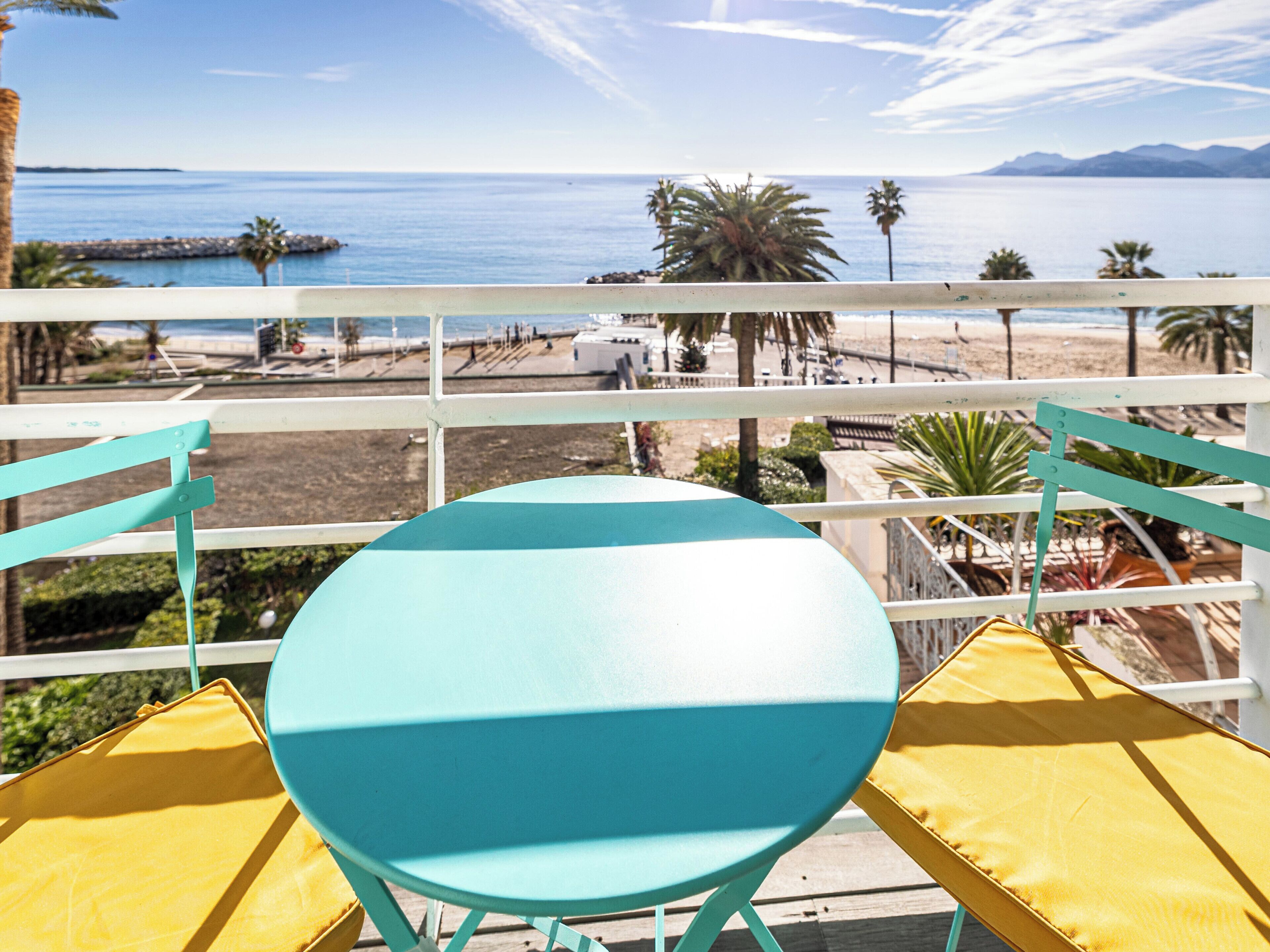 A turquoise and yellow outdoor seating area with a view of the sea and mountains.