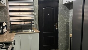 Una cucina moderna con piano cottura integrato, una porta nera e un frigorifero in acciaio inossidabile.