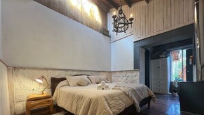 A bedroom with a bed, bedside lamp, and a rustic wooden ceiling. - Oceana Suites San Jose de Maipo (San Jose de Maipo)