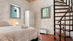 Ein Schlafzimmer mit einem Bett, einem Kleiderschrank, einem Heizkörper und einer Treppe.