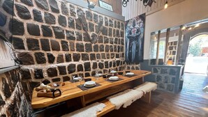 A stone-walled dining area with a wooden table set for six, benches, and a stone fireplace. - Oceana Suites San Jose de Maipo (San Jose de Maipo)