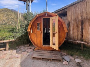 A wooden cabin with a door open, a small window, and a light fixture above the door.