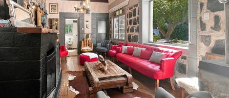 A spacious living room with a fireplace, a red sofa, and a stone wall.