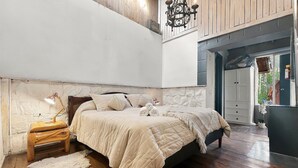 Ein Schlafzimmer mit einem Bett, einem Nachttisch, einer Lampe und einem großen Fenster.