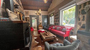 A cozy interior with a fireplace, a red sofa, and a stone wall. - Oceana Suites San Jose de Maipo (San Jose de Maipo)