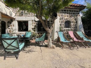 Un edificio de piedra con mesas al aire libre y un árbol que da sombra.