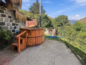 A rustic outdoor setting with a wooden barrel, a stone wall, and a thatched roof structure. - Oceana Suites San Jose de Maipo (San Jose de Maipo)