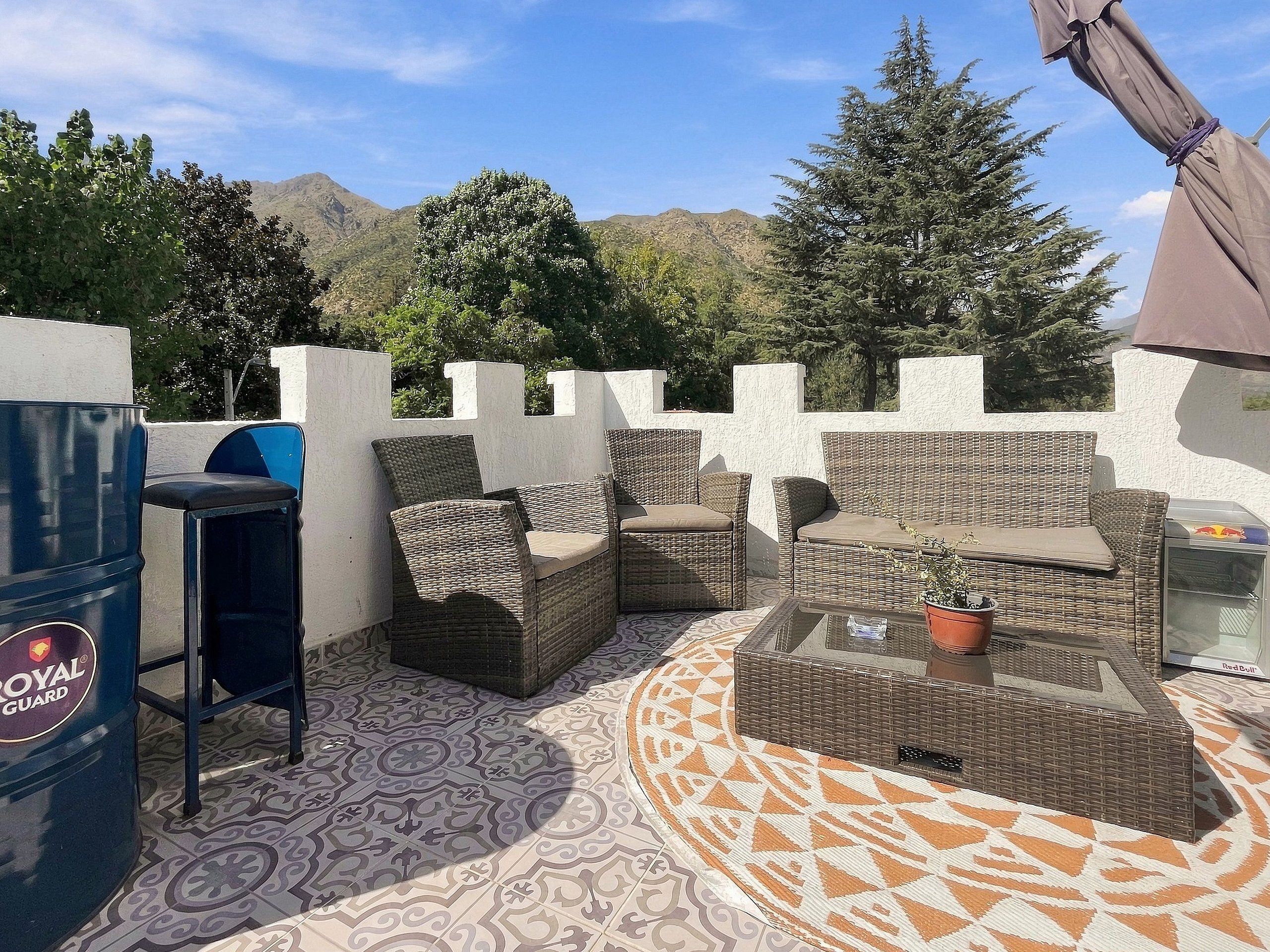 Une terrasse extérieure avec des meubles en osier, un barbecue et un sol à motifs.