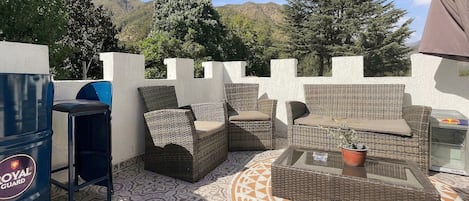 An outdoor patio with wicker furniture, a barbecue grill, and a patterned floor.