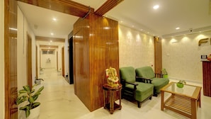 A modern living room with a wooden partition, green sofas, a glass coffee table, and potted plants. - Fly Inn Bangalore Airport (Begur)