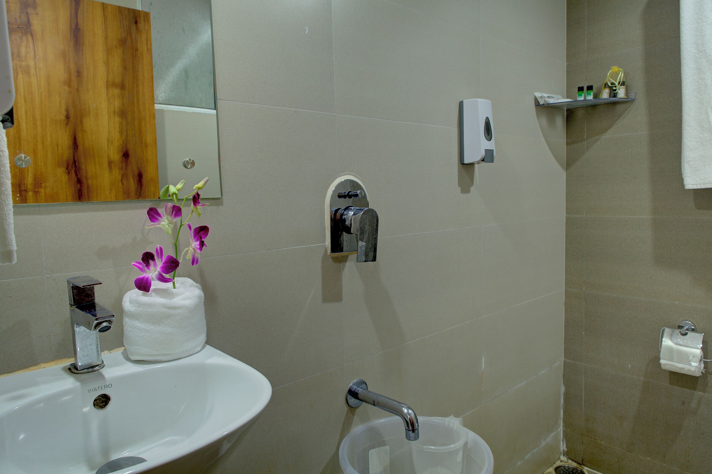 Une salle de bain équipée d’un lavabo, d’un miroir, d’un porte-serviettes et d’une douche.