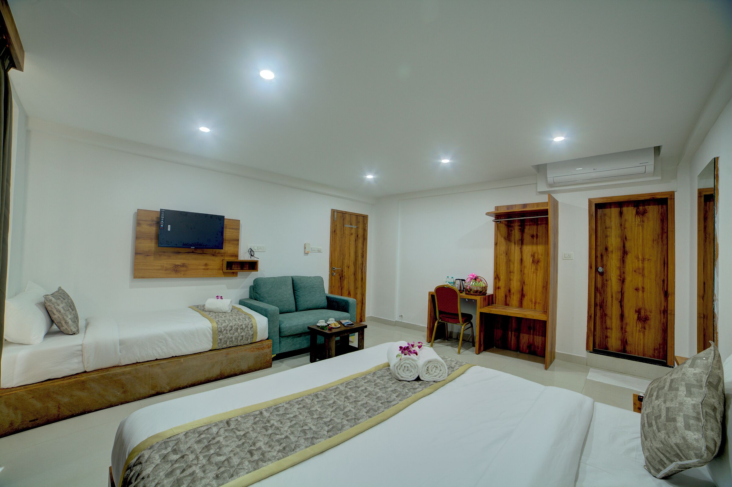 A hotel room with two beds, a desk, a chair, and a TV mounted on the wall.
