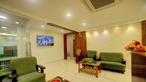 A modern living room with green sofas, a wooden coffee table, and a flat-screen TV mounted on the wall. - Fly Inn Bangalore Airport (Begur)