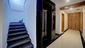 A modern interior with a staircase, elevator, and wooden doors. - Fly Inn Bangalore Airport (Begur)