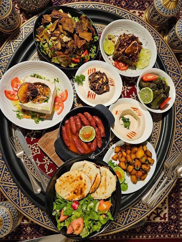 A variety of dishes on a tray, including flatbreads, salads, and a bowl of beans. - Hotel Farid (Dakar)