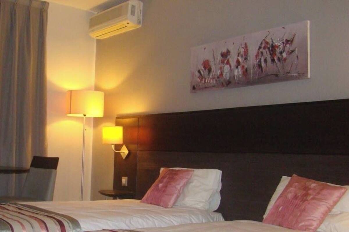 Una habitación de hotel con una cama, un escritorio, una lámpara y un cuadro en la pared.