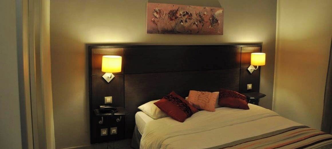 A hotel room with a large bed, two bedside tables, a headboard, and a wall-mounted artwork.