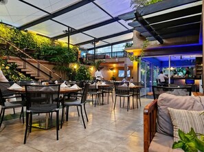 Un espace de restauration intérieur avec des tables et des chaises, un escalier et un coin bar.