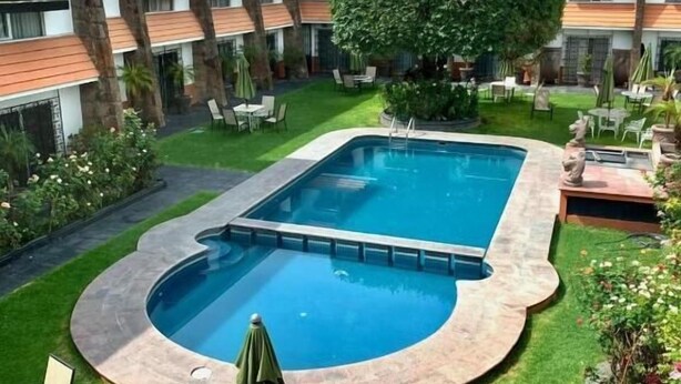 A hotel courtyard with a swimming pool, outdoor seating, and a multi-story building with balconies. - Hotel portal de reyes  (San Juan del Río)