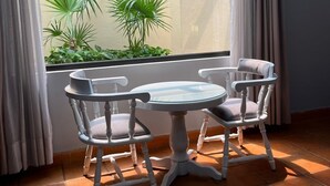 A room with a large window, two white chairs with cushioned seats, and a small round table. - Hotel portal de reyes  (San Juan del Río)