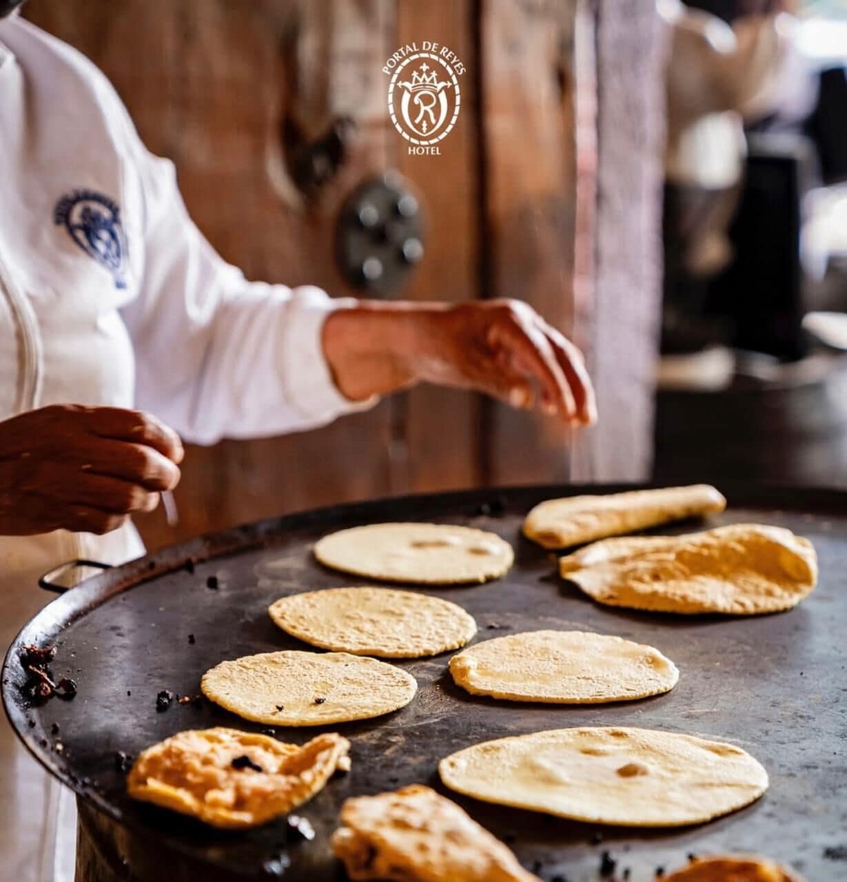 A person cooking tortillas on a griddle.