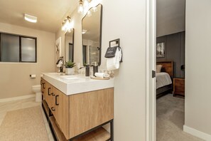 Un baño moderno con tocador de madera, un espejo grande y un perchero para toallas.
