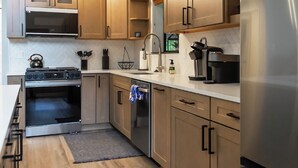 A modern kitchen with wooden cabinets, a stainless steel refrigerator, an oven, and a coffee maker. - Luxury Golf Course Retreat – Sun Country, Cle Elum – Sleeps 8 (Cle Elum)