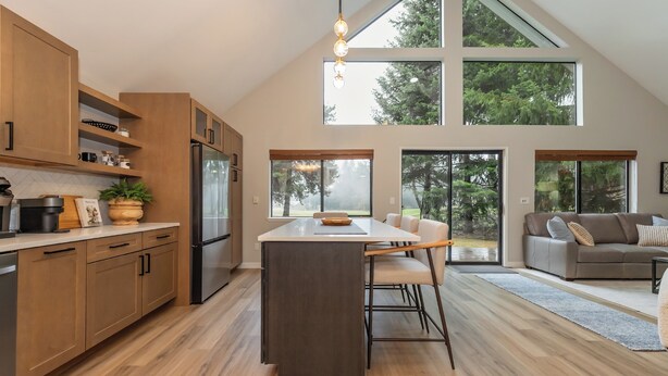 A modern kitchen with wooden cabinets, a central island, and a large window overlooking a forest. - Luxury Golf Course Retreat – Sun Country, Cle Elum – Sleeps 8 (Cle Elum)