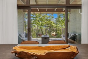 A modern room with a large window, a wooden table, and a sofa. - Elegantly Styled 4BDR  Spa - Tremblant (Mont-Tremblant)