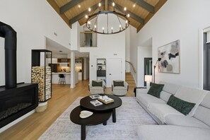 A spacious living area with a fireplace, a round coffee table, a sofa, and a staircase leading to an upper level. - Elegantly Styled 4BDR  Spa - Tremblant (Mont-Tremblant)