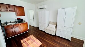A compact kitchen with wooden cabinets, a microwave, and a plaid rug. - The Starland Loft Apartment- Savannah, GA (Savannah)