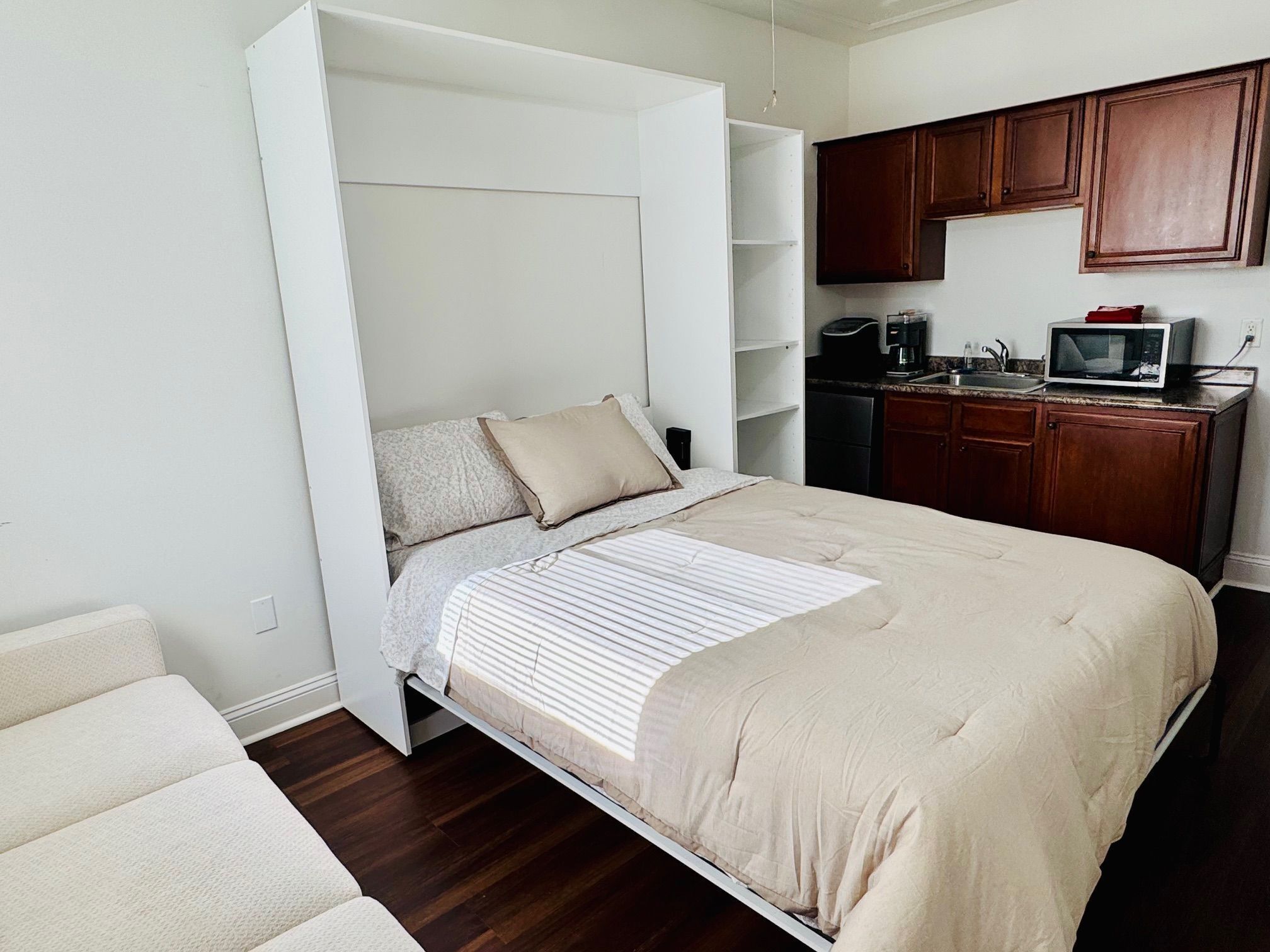 A compact bedroom with a bed, a small kitchenette, and a built-in wardrobe.