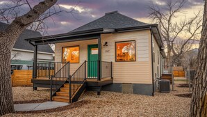 A single-story house with a green door, a covered porch, and a small staircase leading to the entrance. - New- Encore Retreat- Sauna-Fire Pit- Theater Room (Colorado Springs)