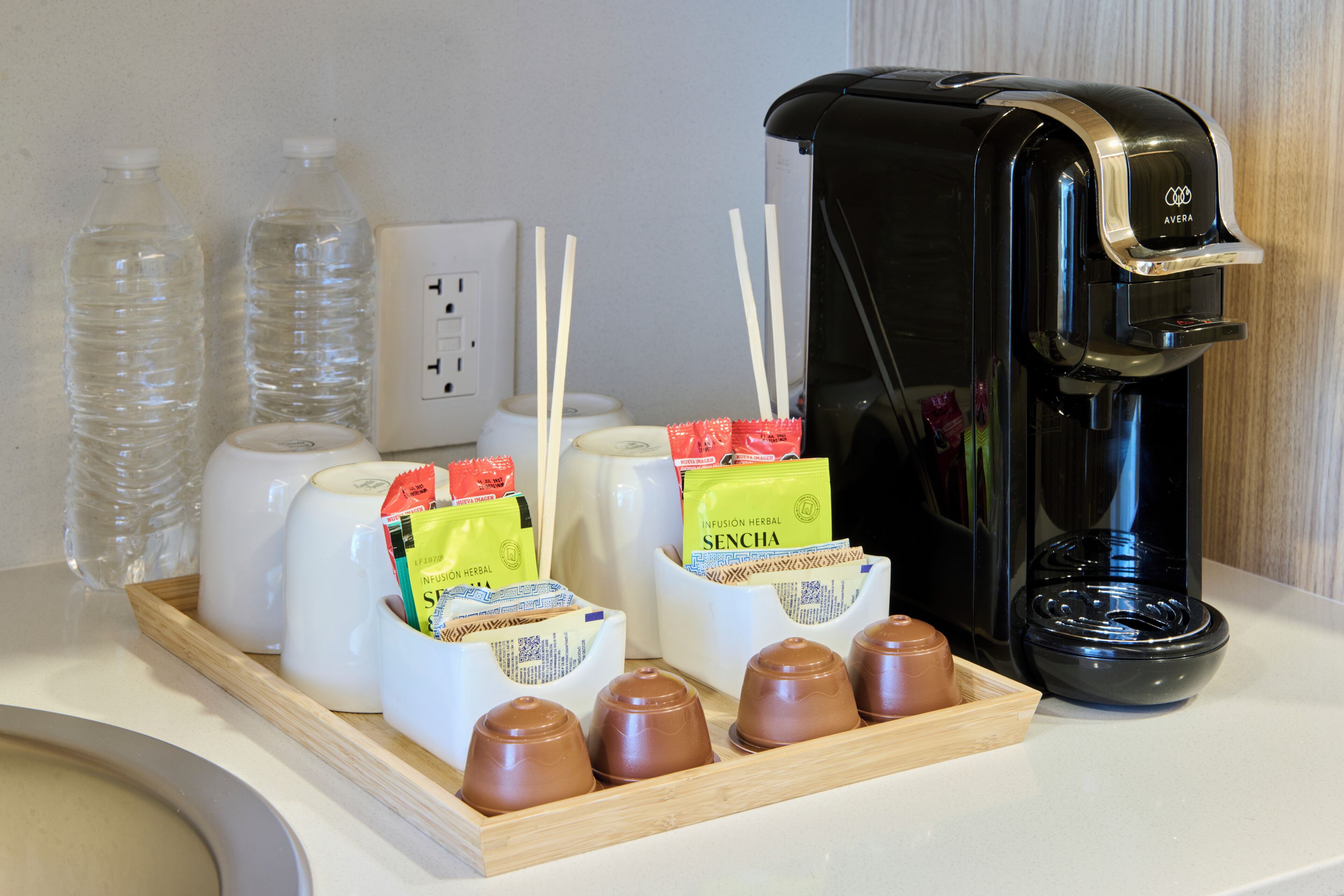 Eine Kaffeemaschine, Wasserflaschen und ein Tablett mit Kaffeekapseln und Teebeuteln.