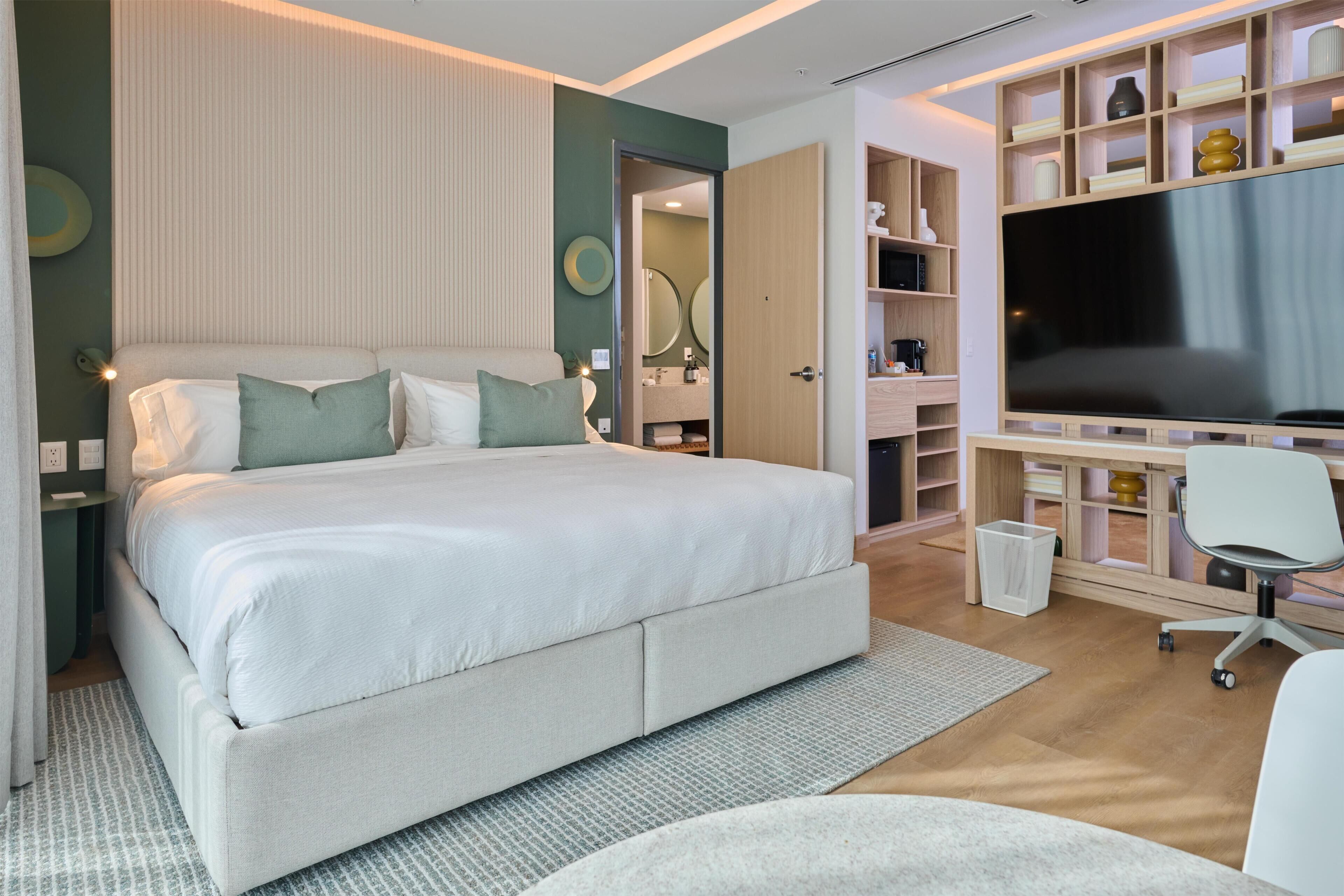 Une chambre moderne avec un grand lit, une télévision, un bureau et un dressing.