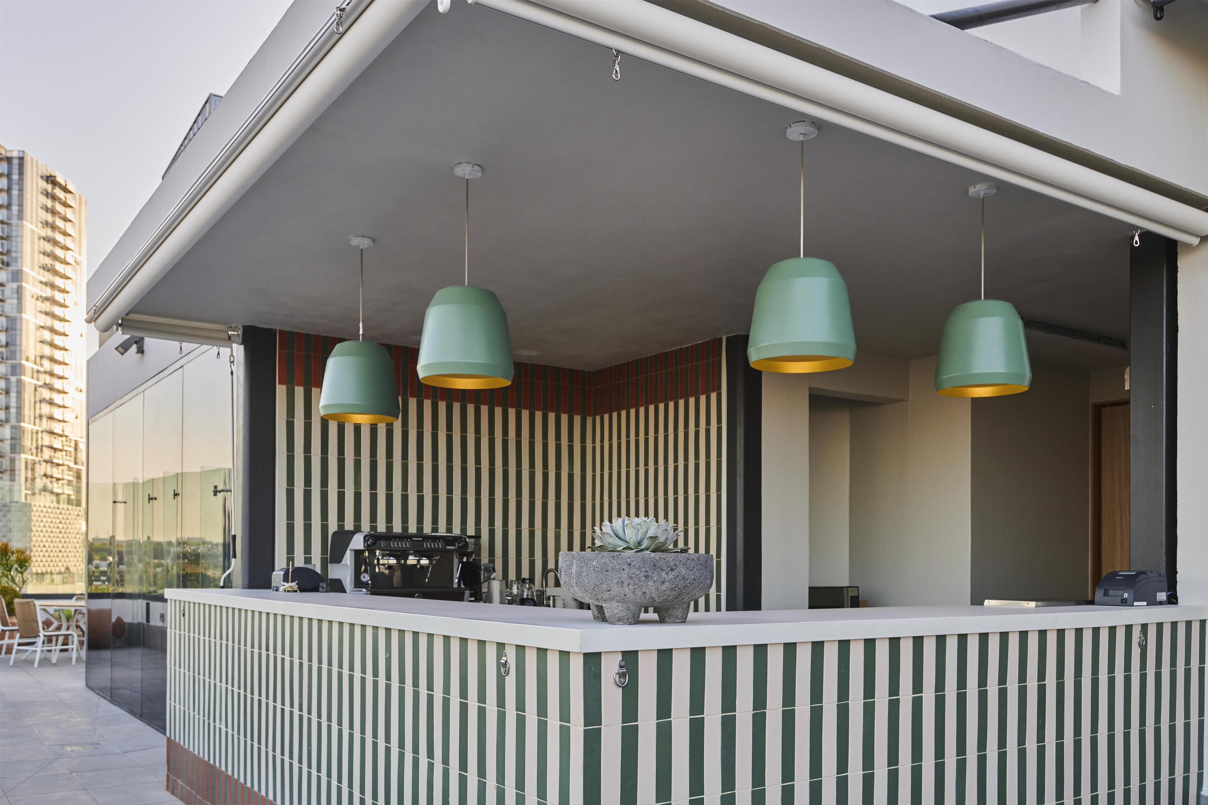 A modern reception area with a counter, green pendant lights, and a stone planter.