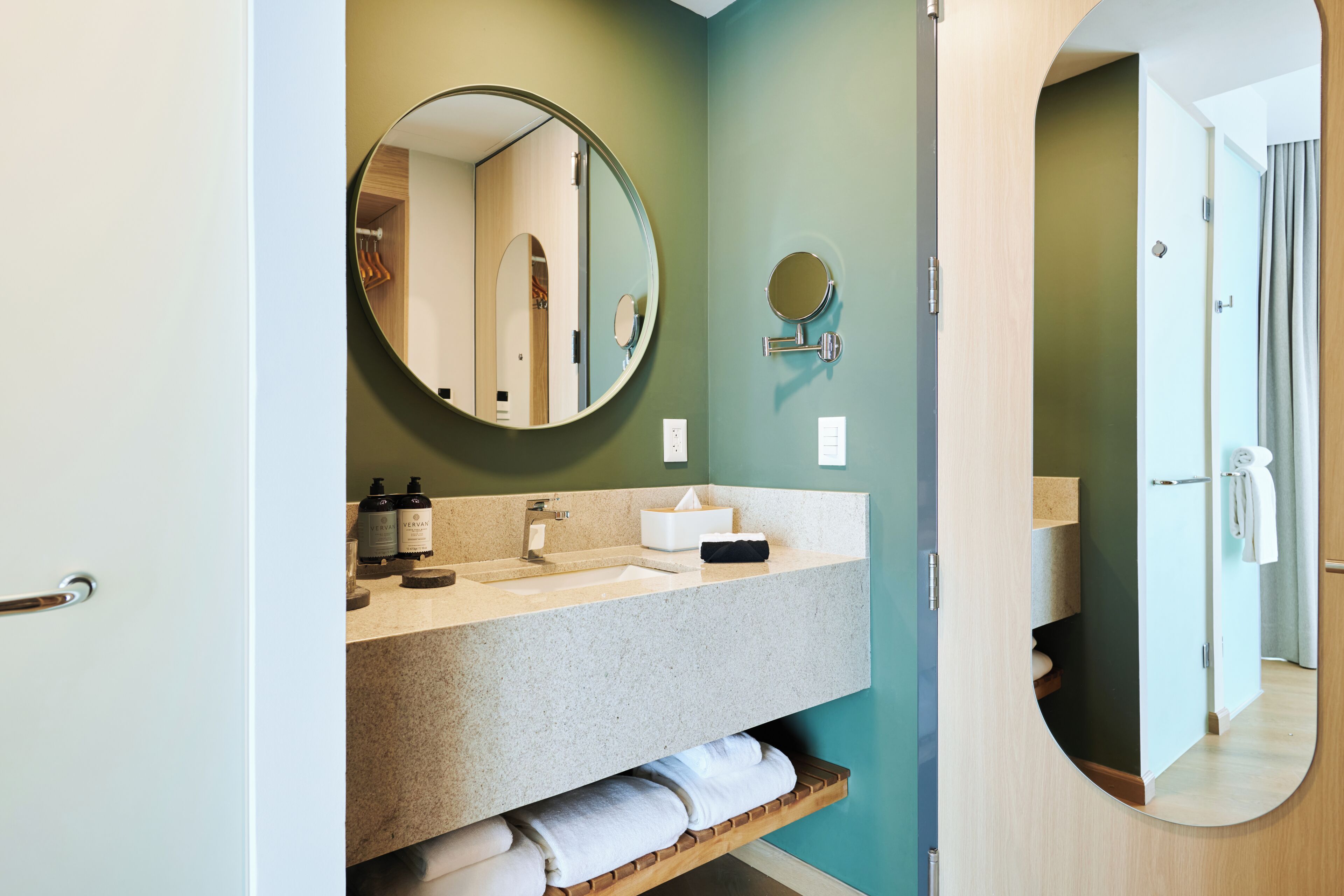 A bathroom with a round mirror, a sink, and a towel rack.
