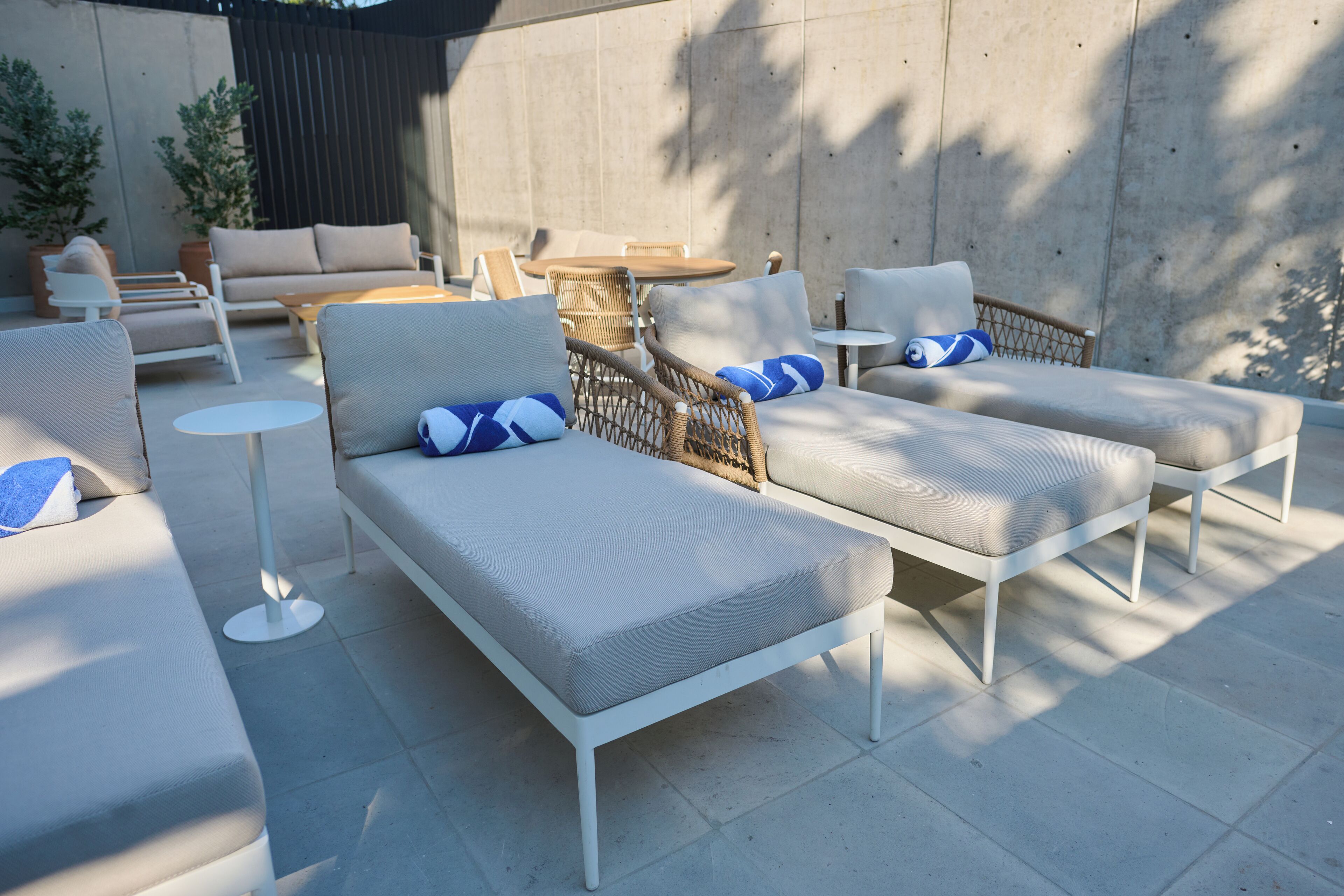 Un espace patio doté de plusieurs options d’assises, notamment des canapés et des fauteuils, une petite table ronde et une plante en pot.