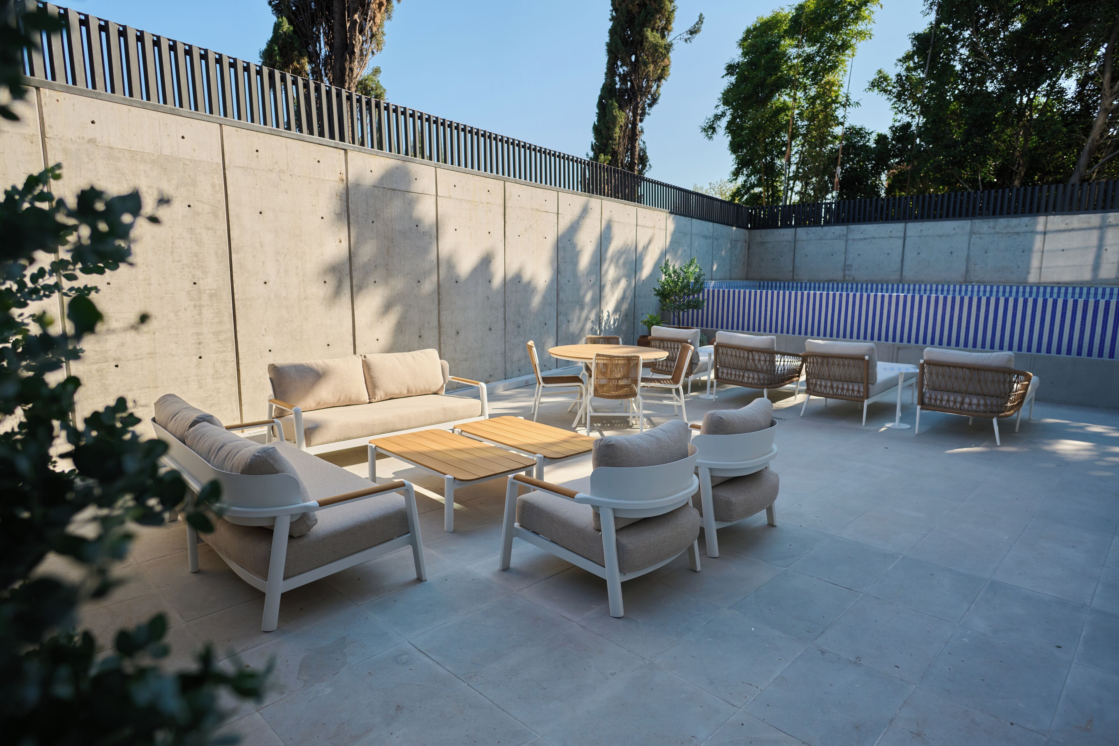 Une terrasse extérieure aménagée avec des meubles modernes, notamment des canapés et des fauteuils, disposés autour d’une table centrale.