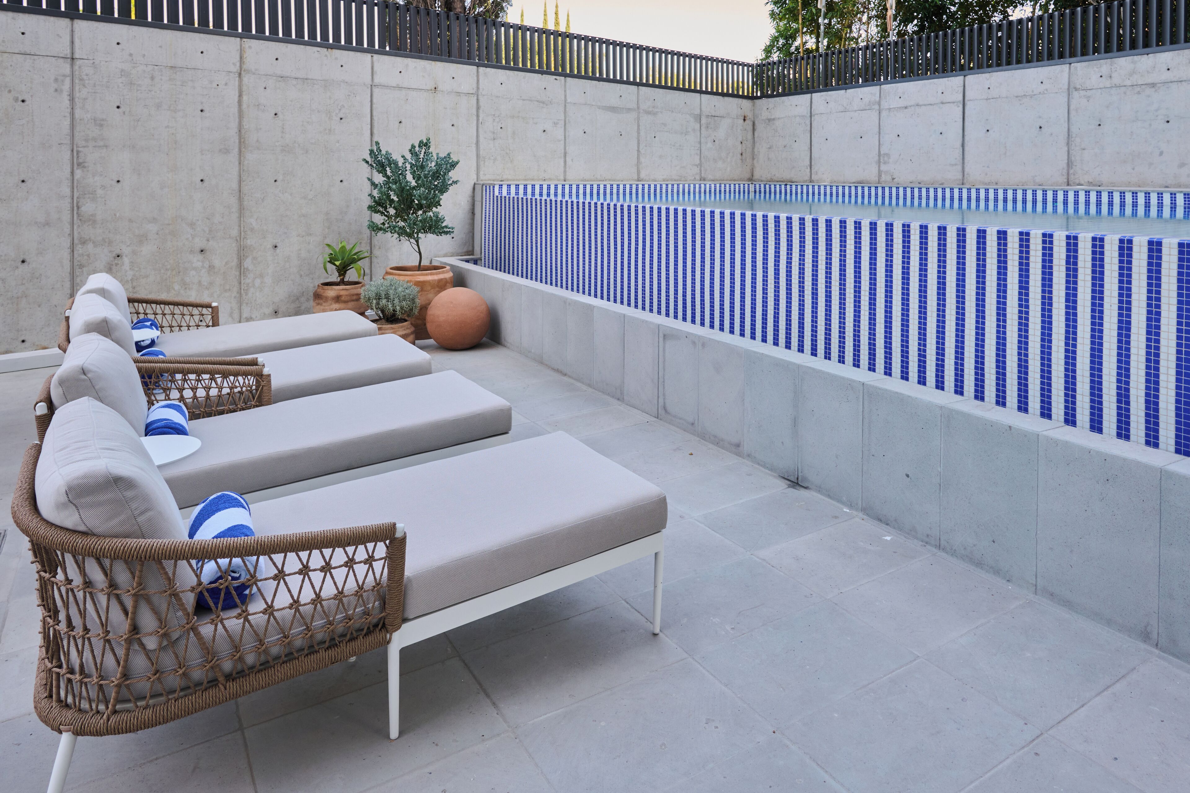 Zona de piscina en la azotea con sillones de descanso y piscina con azulejos.