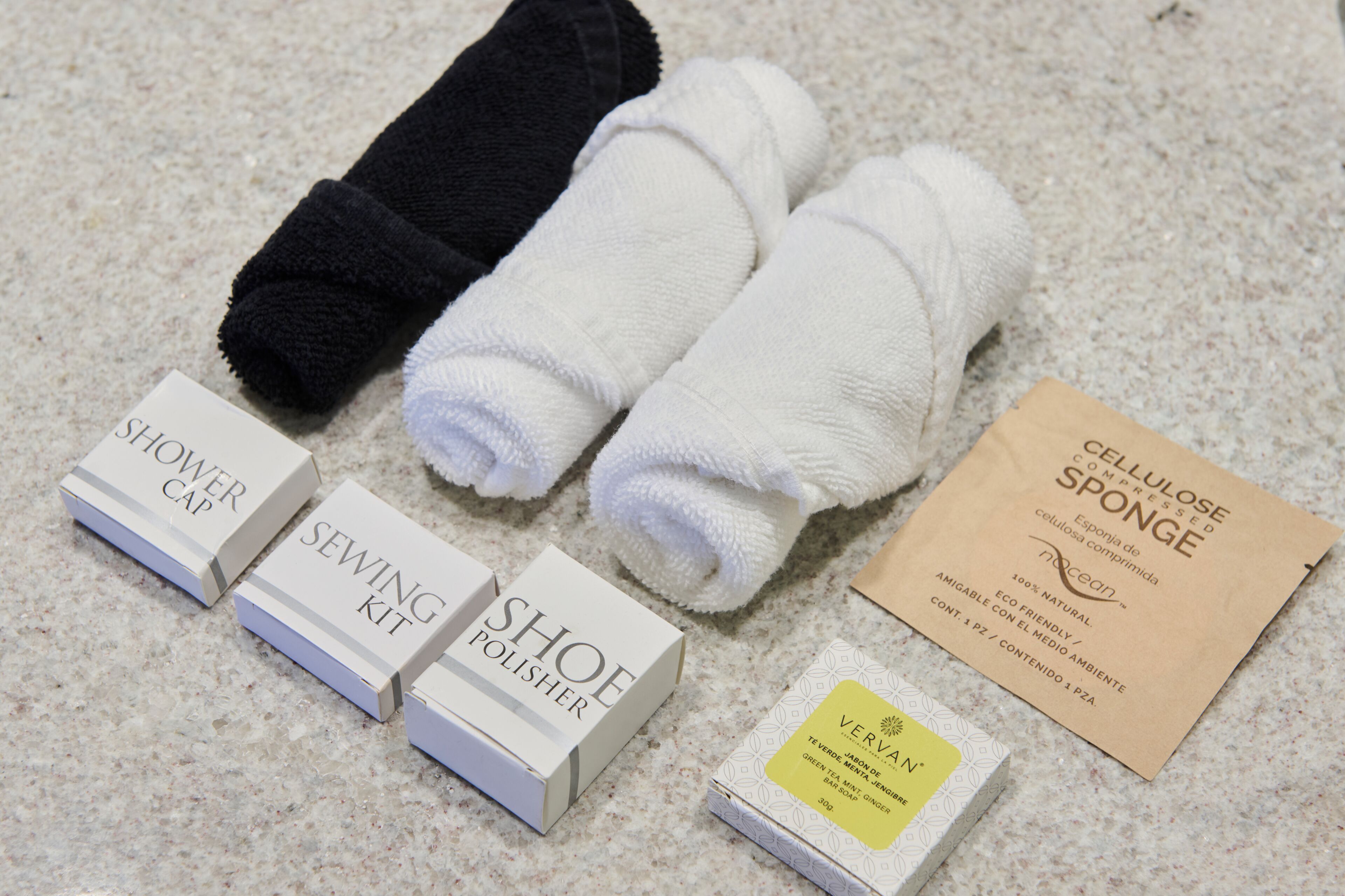 A set of toiletries including a shower cap, sewing kit, shoe polish, and a sponge.