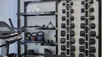 Ein Fitnessraum mit Laufband, Kettlebells, Hanteln und einem Handtuchständer.