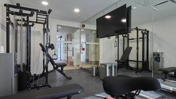 A modern gym with exercise equipment, a bench, and a treadmill.