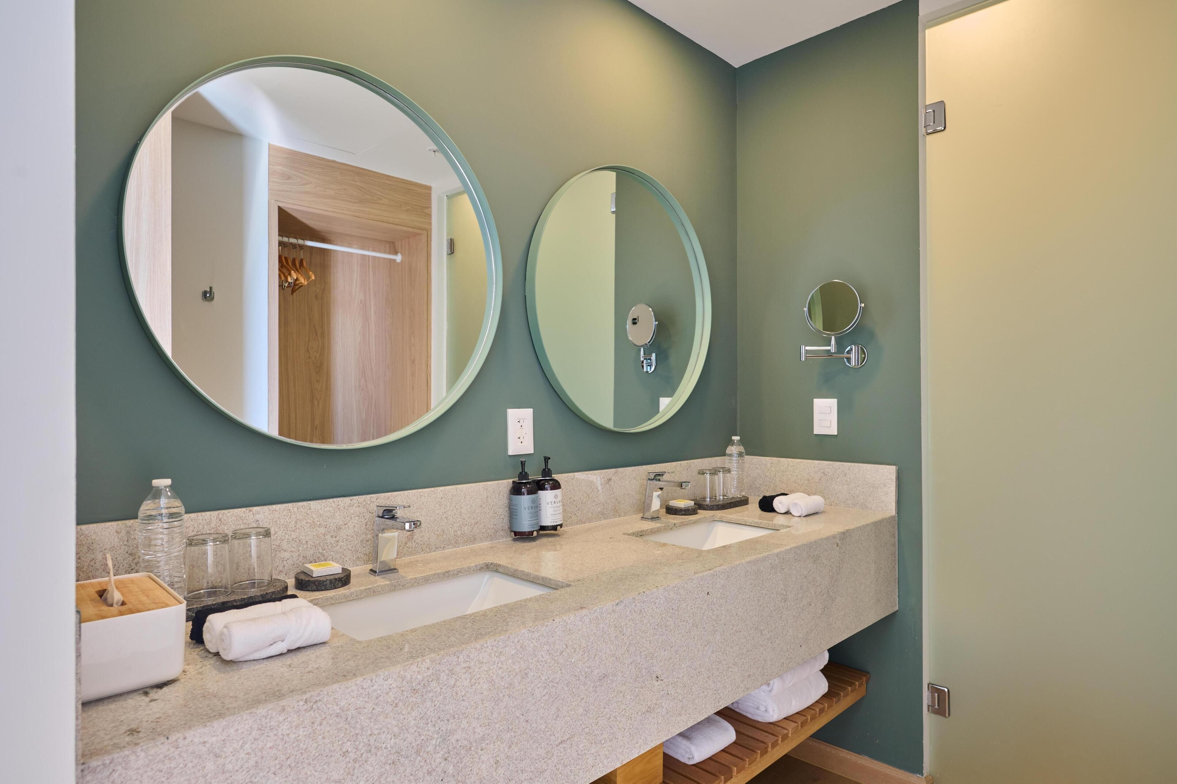 A bathroom with two sinks, a mirror, and a wooden shelf.