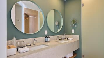 A bathroom with two sinks, a mirror, and a wooden shelf.