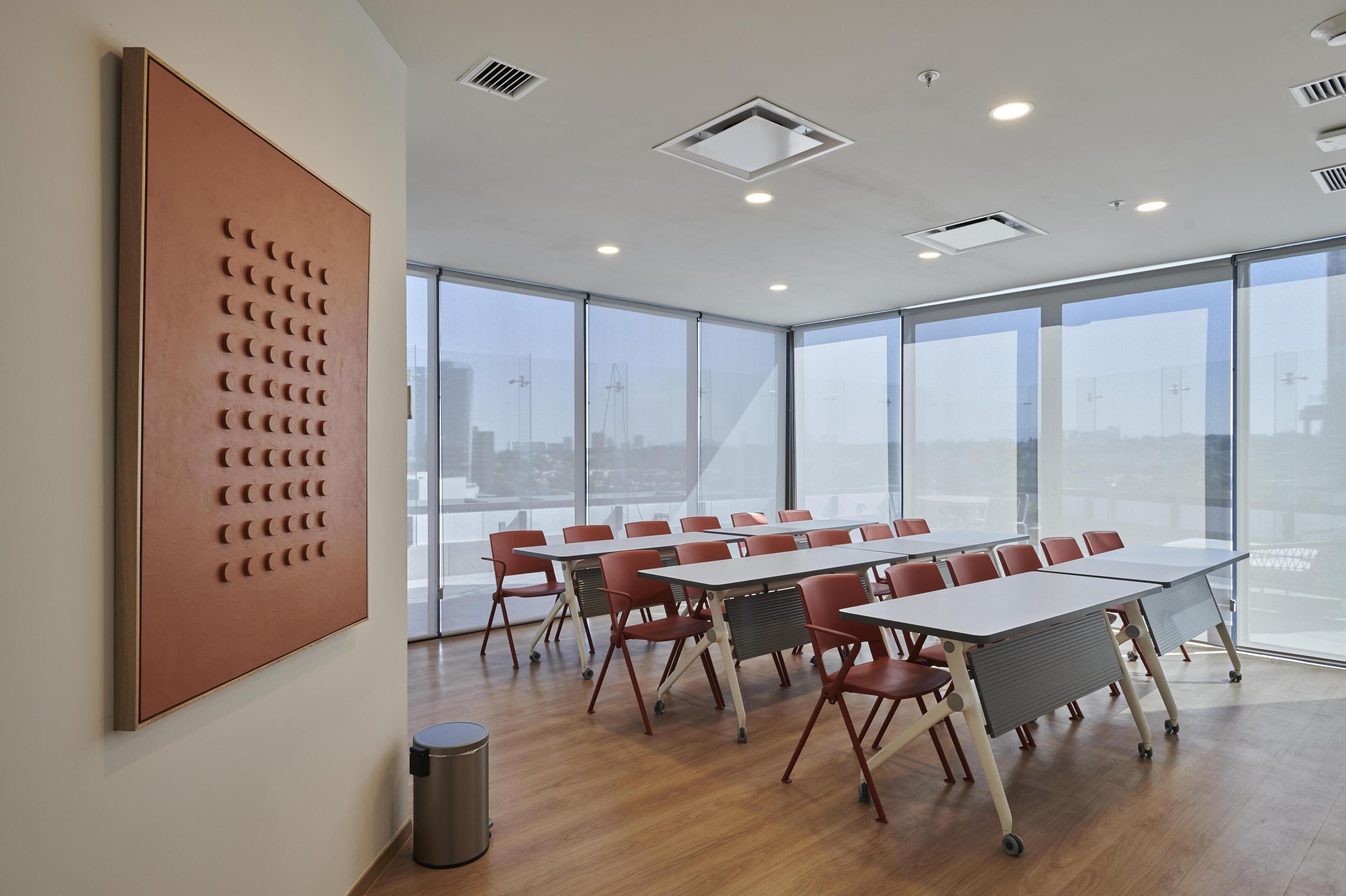 A conference room with large windows, a long table, and red chairs.