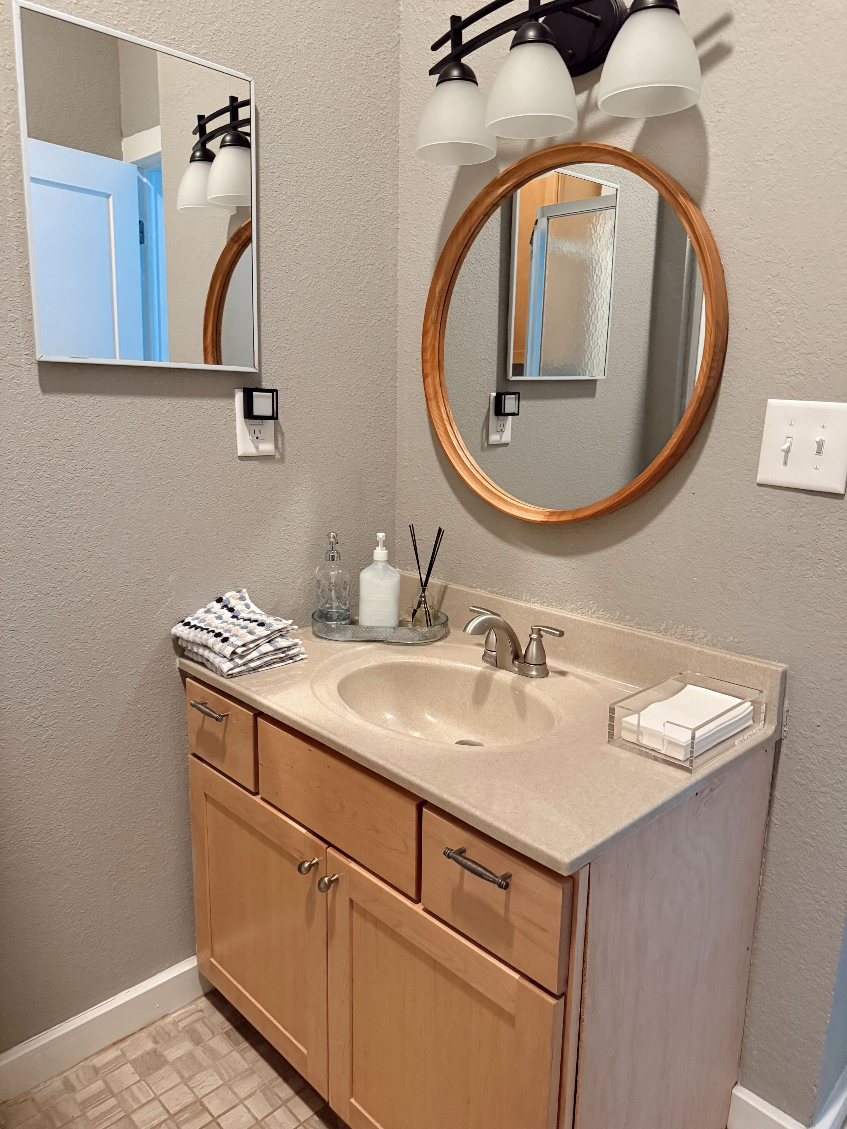 Une salle de bain équipée d’un lavabo, d’un miroir, d’un meuble et d’appliques murales.