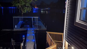 Un muelle que se extiende desde una casa con terraza y barandilla de madera.