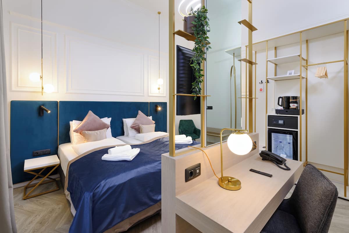 A hotel room with a bed, bedside table, desk, chair, and a mirror.