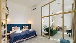 A modern hotel room with a large bed, a sitting area with a green sofa, and a mirrored wall. - SOPHIA PALACE Hotel Budapest (Budapest)